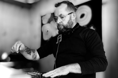 Un homme portant des lunettes et un casque audio manipule un équipement électronique dans un environnement intérieur.
