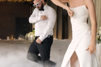 Un couple en tenue de mariage danse sur une piste entourée de fumée et de guirlandes lumineuses suspendues.