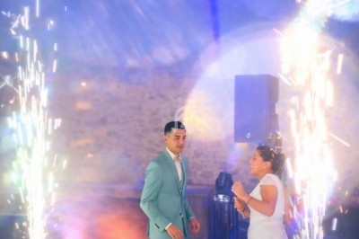 Un couple danse lors d'une fête, entouré d'effets pyrotechniques lumineux dans une ambiance festive.