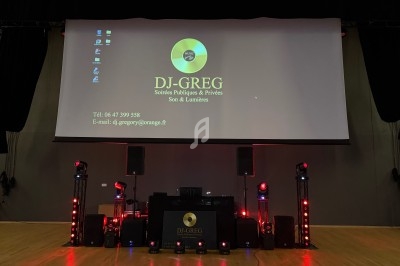 Équipement de sonorisation et éclairage installé devant un écran affichant les coordonnées d'un DJ.