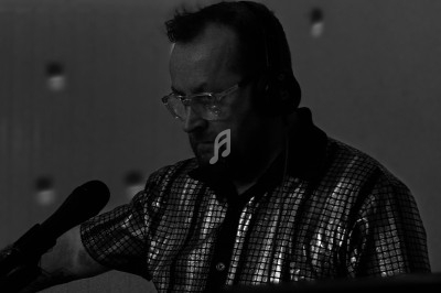 Un homme portant un casque audio mixe de la musique sur une table de mixage dans une ambiance tamisée.