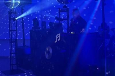 Un DJ mixe derrière une table éclairée par des projecteurs et des boules à facettes dans une ambiance lumineuse bleutée.