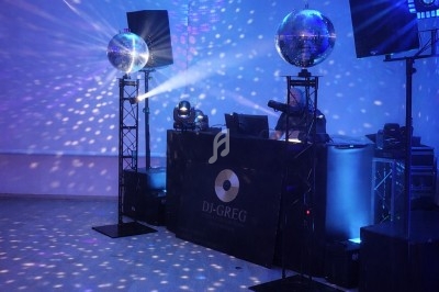 Salle éclairée par des jeux de lumière colorés avec une table de mixage et des boules à facettes.