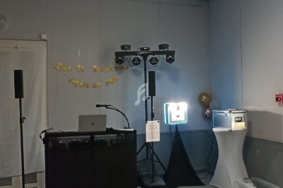 Matériel de sonorisation et éclairage installé dans une salle, avec ballons et décoration murale festive.