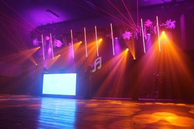 Jeu de lumières colorées avec lasers rouges et projecteurs orange éclairant une scène dans une salle sombre.