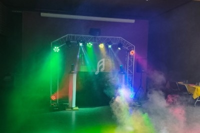 Jeux de lumières colorées et fumée sur une piste de danse dans une salle sombre avec tables en arrière-plan.