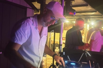 Un DJ mixant de la musique sur une table de mixage éclairée, dans un environnement nocturne.