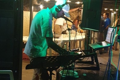 Un DJ mixe de la musique en extérieur sous un éclairage tamisé, avec des invités en arrière-plan.
