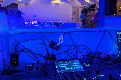 Console de DJ éclairée en bleu dans une salle décorée pour un événement avec des drapés suspendus au plafond.