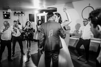 Un couple danse au centre d'une salle lors d'une réception, entouré d'invités applaudissant.