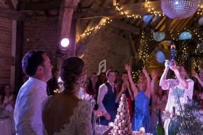 Un couple de mariés regarde une animation festive dans une salle décorée avec guirlandes lumineuses et boules scintillantes.