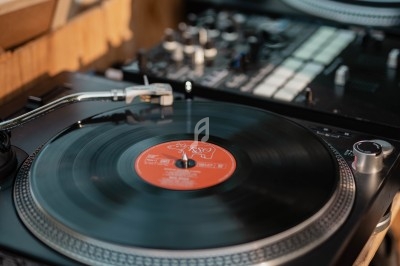 Platine vinyle en fonctionnement avec un disque noir et rouge, entourée d'équipements de mixage.