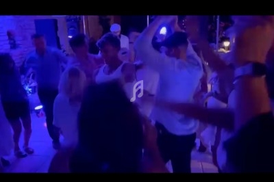 Des personnes dansent dans une ambiance festive et éclairée par des lumières colorées dans une salle.