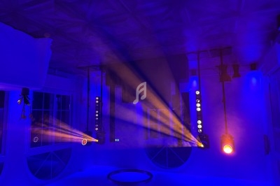 Éclairage scénique avec projecteurs colorés diffusant des faisceaux orange et bleus dans une pièce sombre.