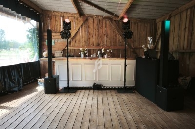 Installation de matériel audio et éclairage devant un bar en bois dans un espace intérieur à structure en bois.